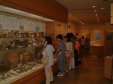 常設展示室の展示ケースの展示品をみる人々の写真