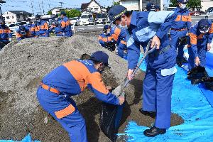 消防団員とともに土のうを作成する新井藤岡市長