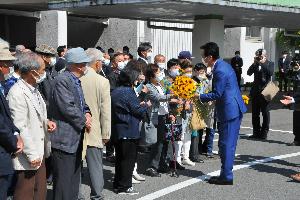 初登庁で支援者からひまわりの花を渡される新井市長