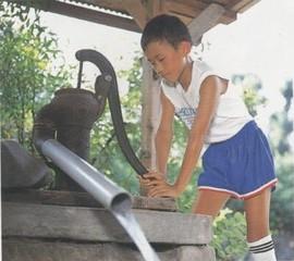 井戸水をくむ少年の写真。