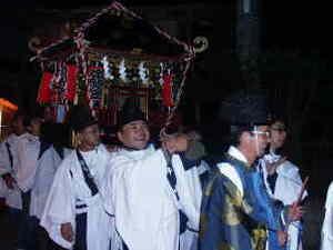 別殿を出立する神輿を担ぐ白い装束の人々の写真